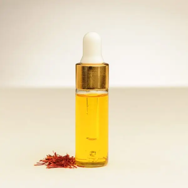 Eine 4 ml Flasche ätherisches Safranöl mit Safranfäden daneben.