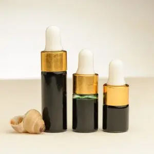 Drei Fläschchen mit ätherischem Seetangöl zu 2 ml, 3 ml und 4 ml neben einer Muschel
