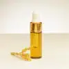 4 ml Fläschchen ätherisches Mimosenöl neben einer Mimosenblüte