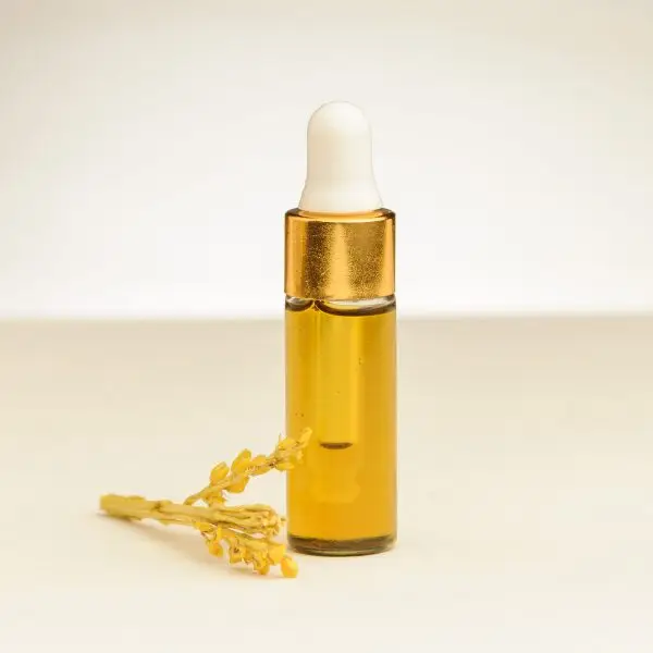 4 ml Fläschchen ätherisches Mimosenöl neben einer Mimosenblüte