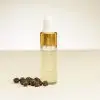 Fläschchen mit schwarzem Pfeffer ätherischem Öl und schwarzen Pfefferkörnern