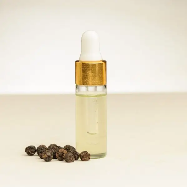 Fläschchen mit schwarzem Pfeffer ätherischem Öl und schwarzen Pfefferkörnern